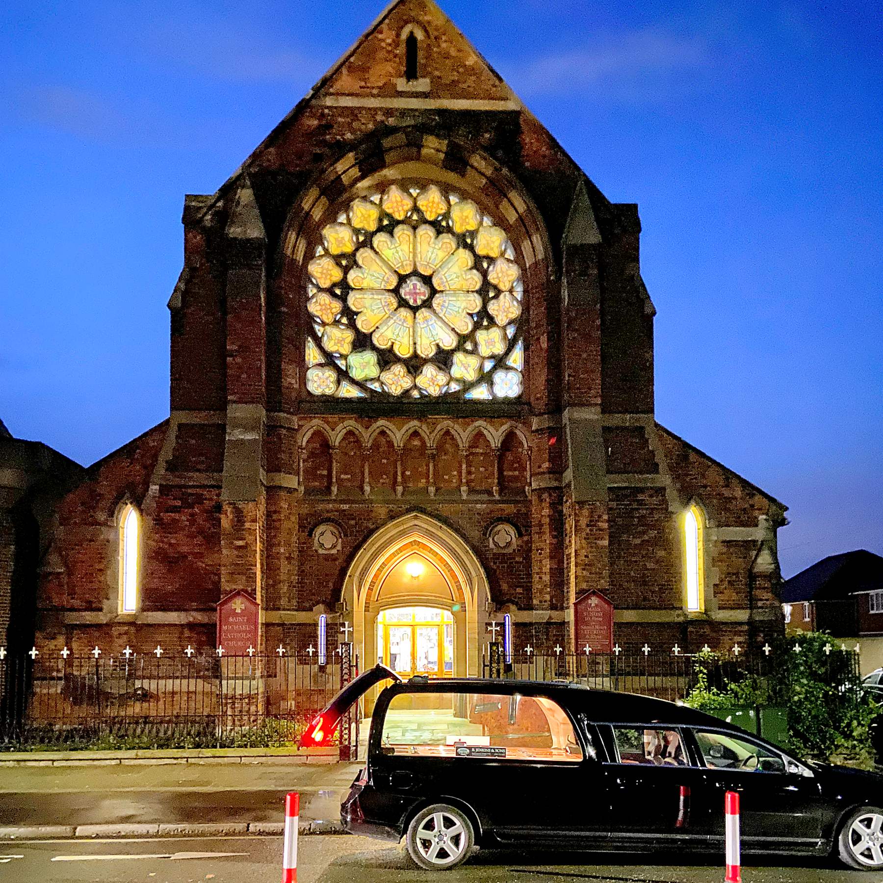 A hearse outside St Michael's Catholic Church at dusk