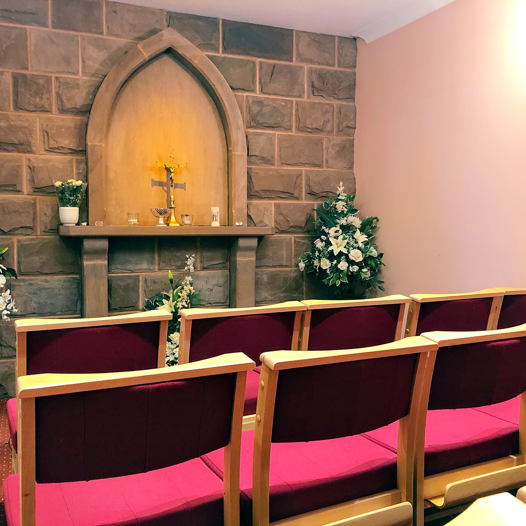 Inside one of the chapels of rest, with a stone arch, a gilded crucifix and white lilies