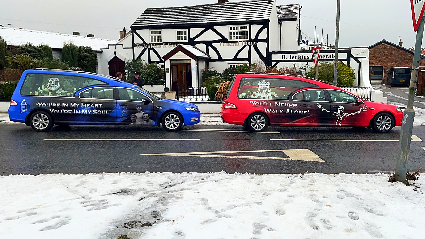 The Everton Blue and Liverpool Red hearses parked outside the funeral home in the snow